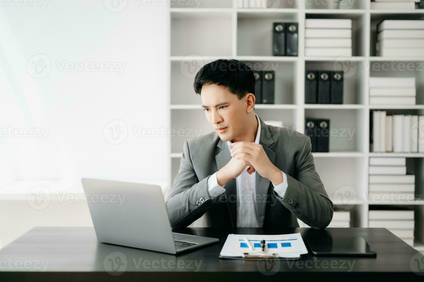 Frustrated young businessman working on a laptop computer sitting at his working place in office photo