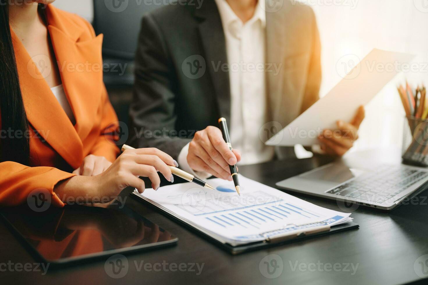 Business documents on office table with smart phone and calculator digital tablet and graph business with social network diagram and two colleagues discussing data working in the office photo