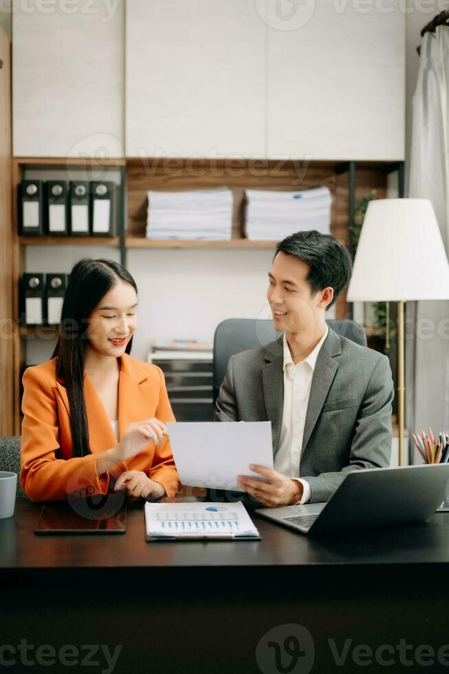 Two Asian businesswoman discuss investment project working and planning strategy with tablet laptop computer in  office. photo