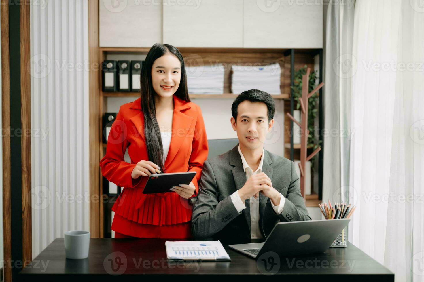 Two Asian businesswoman discuss investment project working and planning strategy with tablet laptop computer in  office. photo