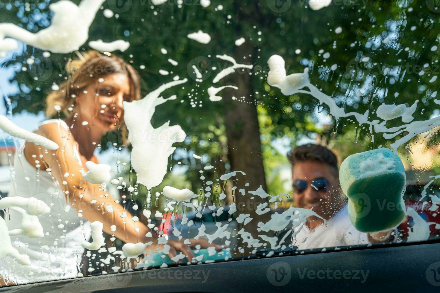 happy middle aged couple with man sitting on wheelchair washing car at public car wash photo