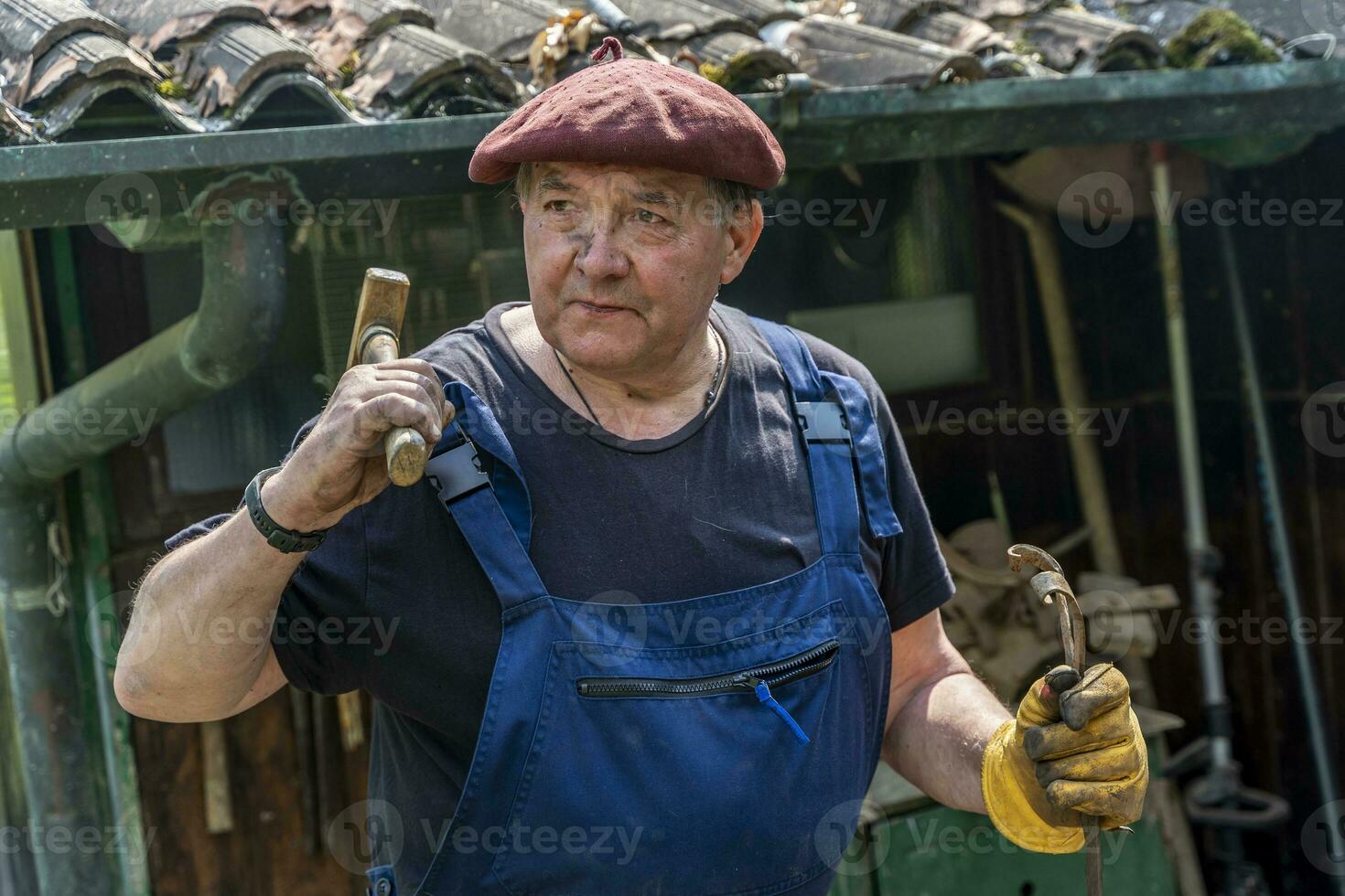 portrait of mature blacksmith. Iron worker in workshop outdoors in the countryside photo