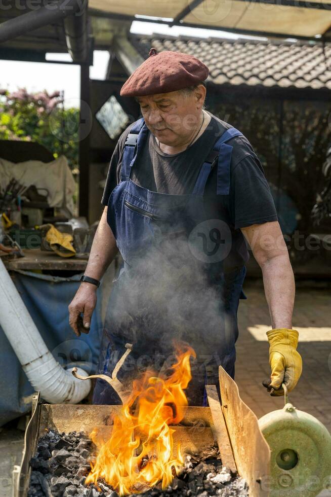 blacksmith is burning a metal bar to give it a new shape photo
