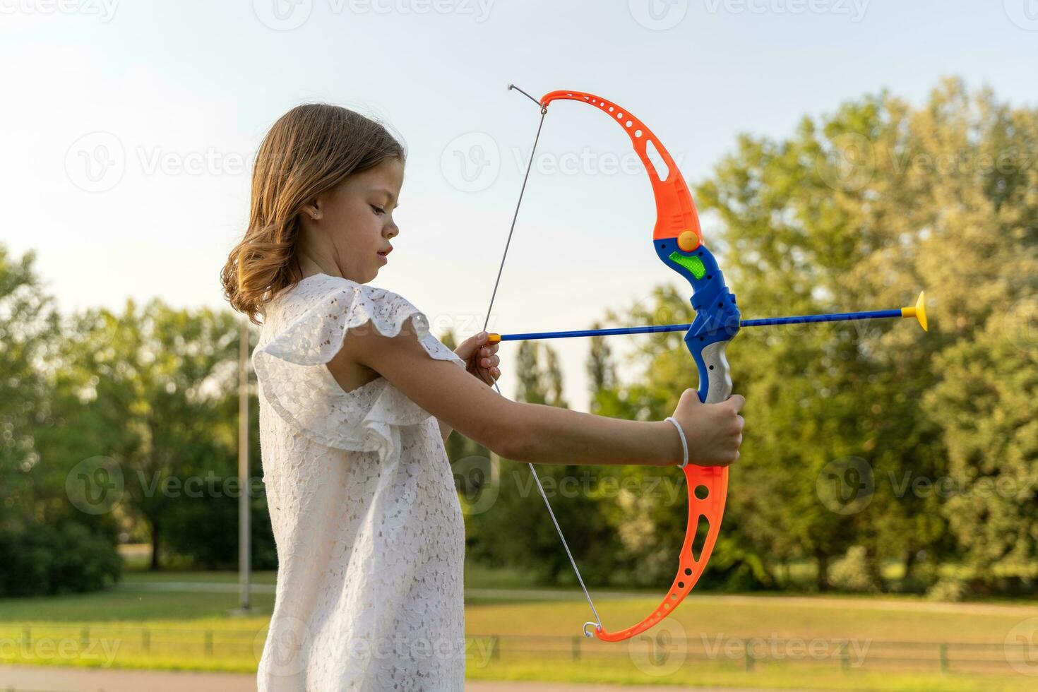 linda pequeño niña es jugando con un juguete arco y flecha foto