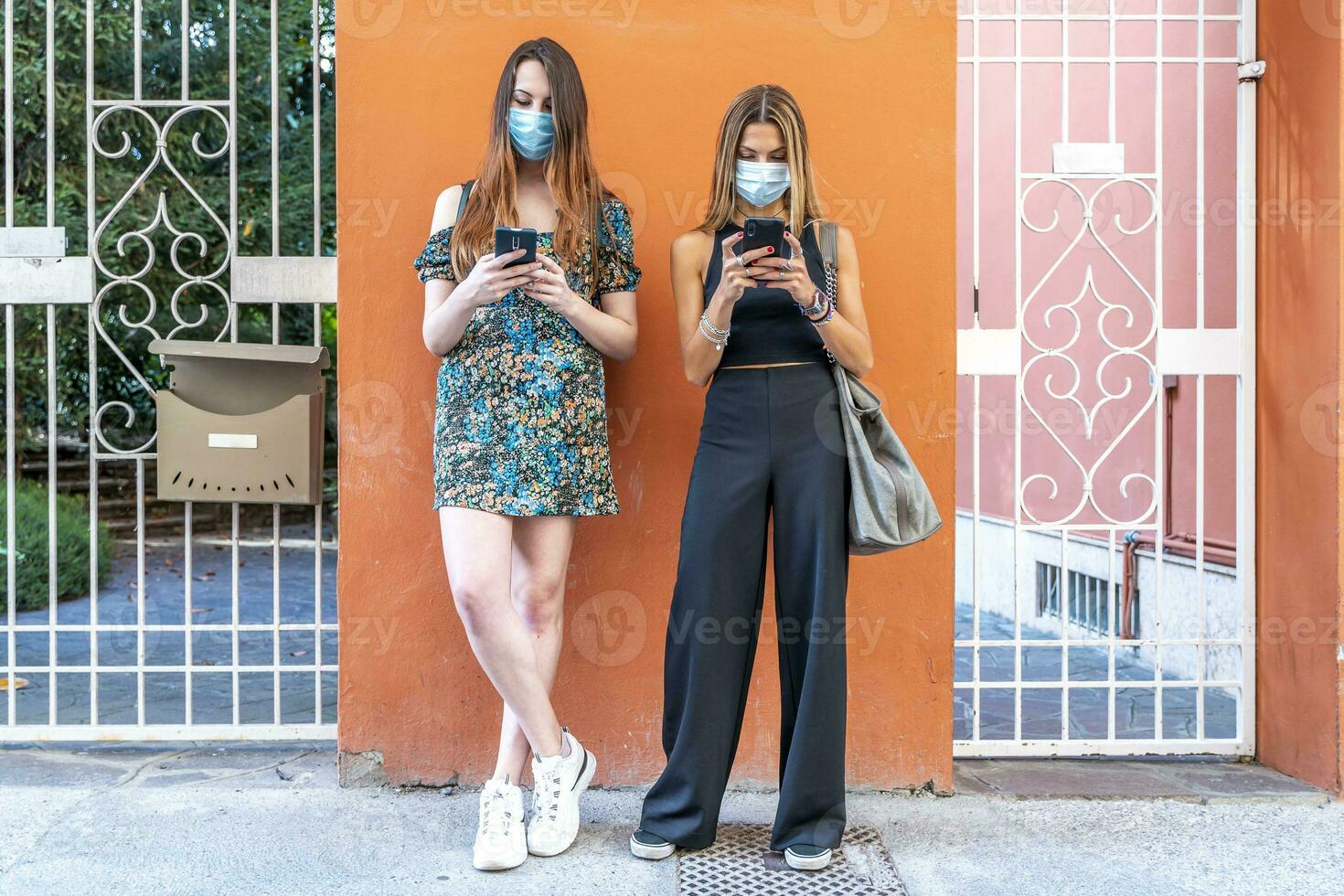 Pareja de multirracial amigos con cara mascaras utilizando teléfonos inteligentes foto