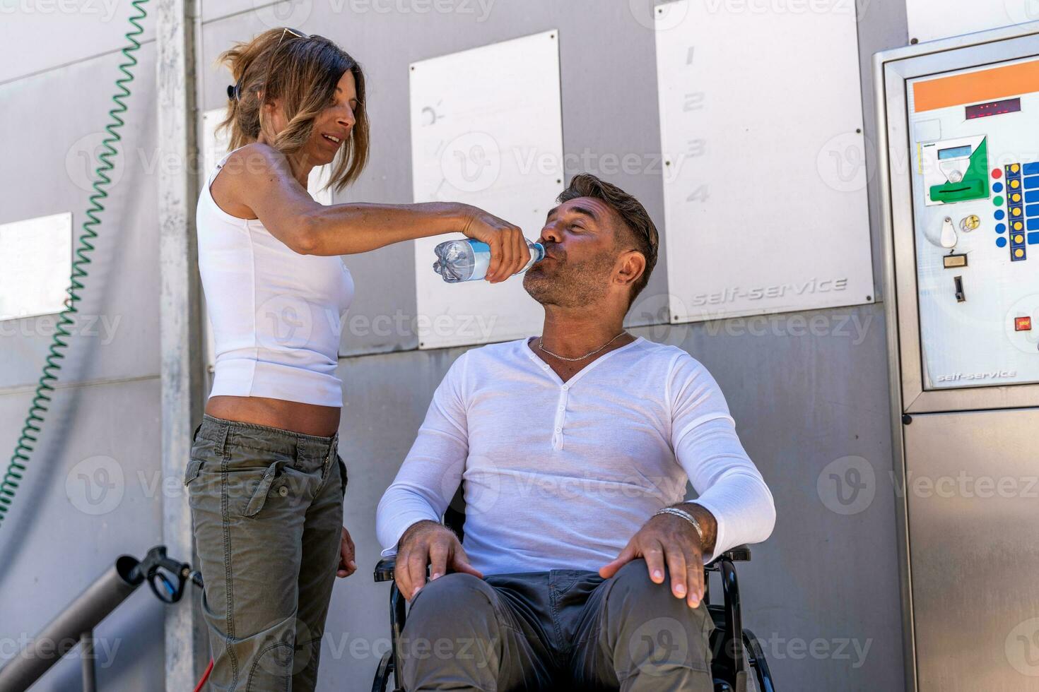 beautiful woman is giving her boyfriend a drink on a break while they wash the car at the car wash photo