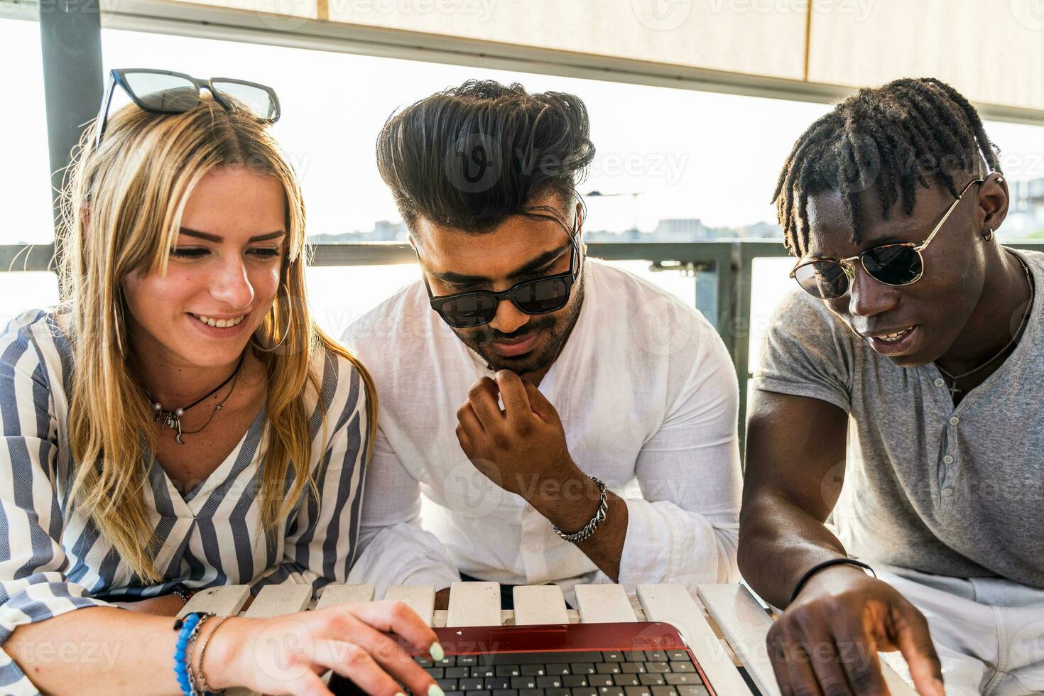 small group of multiethnic friends having fun surfing the net on the laptop photo