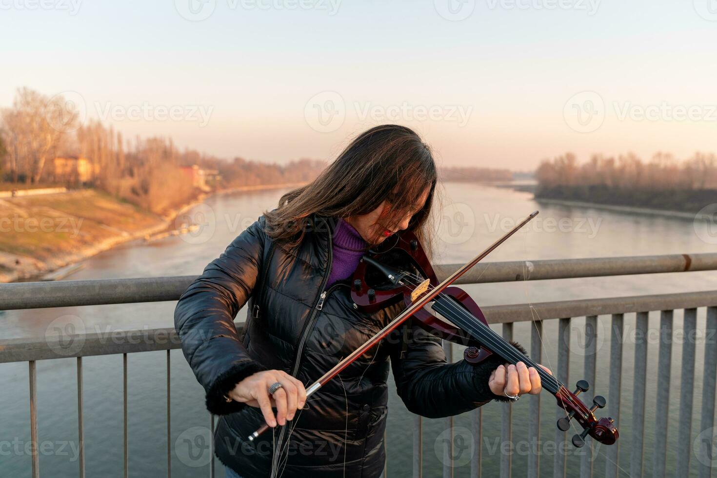 atractivo medio Envejecido mujer jugando un eléctrico violín al aire libre foto