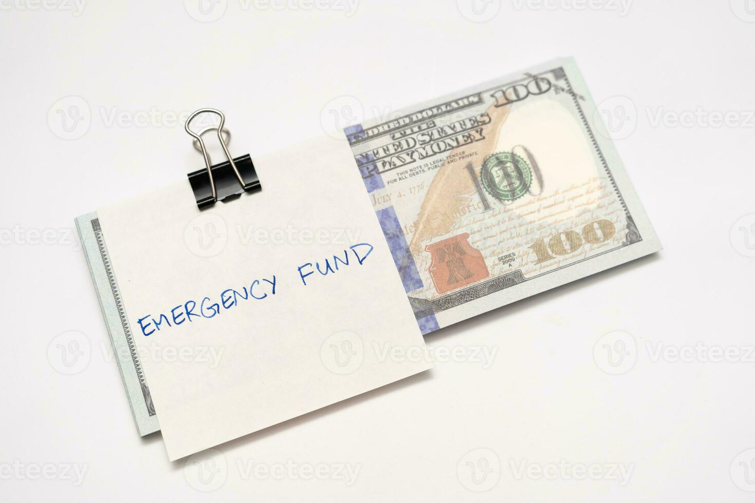 US dollars in paper clip on white background with note written EMERGENCY FUND. Concept of money saving goal. Financial planning saving money for purpose of rainy day crisis. photo