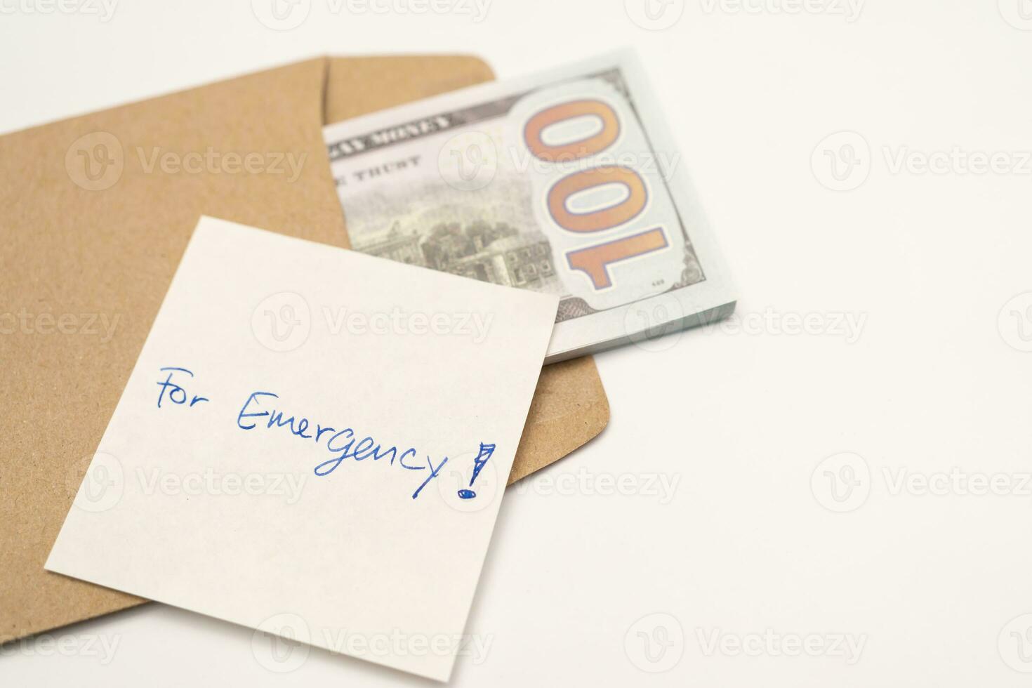 Dollars cash money in craft paper envelope and paper note with text written FOR EMERGENCY. concept of financial planning saving money goal on purpose of rainy day. photo