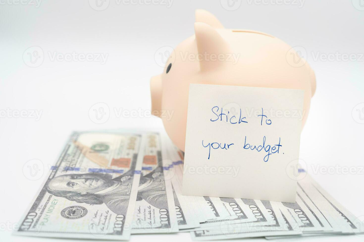 Text written note STICK TO YOUR BUDGET and Piggy bank on US Dollars. concept of financial planning to save money by spending less. Finance and business concept. isolated background. photo
