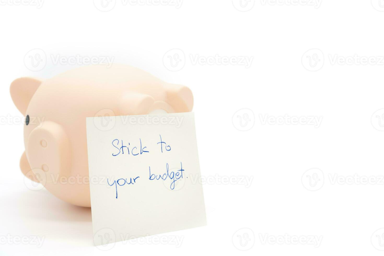 Text written note STICK TO YOUR BUDGET and upside down Piggy bank. concept of financial planning to save money by spending less. Finance and business concept. isolated on white background. photo