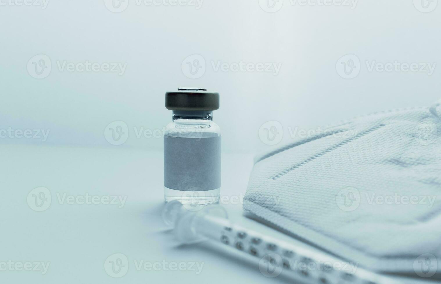 Vaccine in vial, syringe and face mask over white background and copy space. Medical concept. Insurance, laboratory, subcutaneous injection. Disease treatment immunization. photo