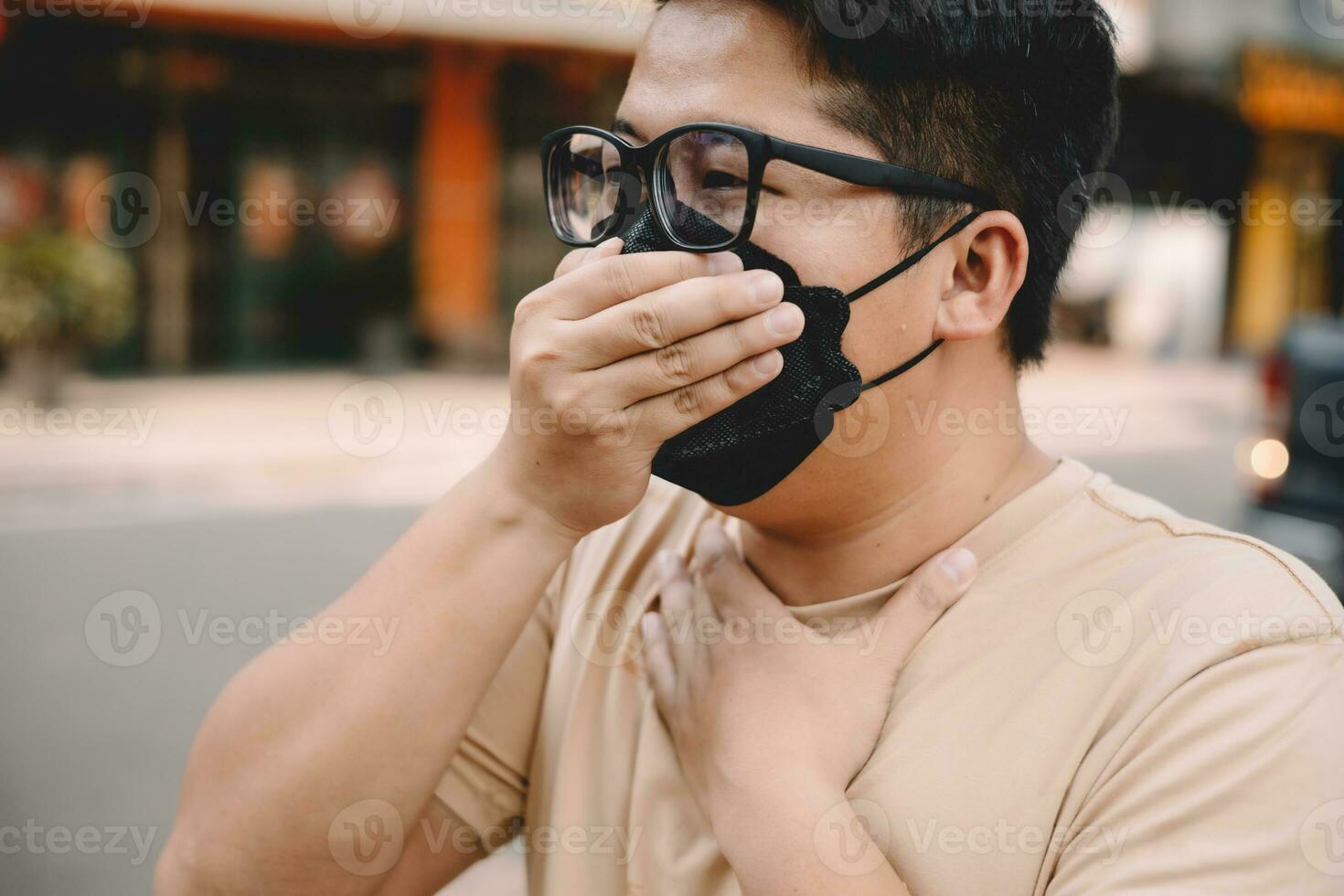 Asian young man wearing face mask to protect PM 2.5, protect pollution, anti smog and viruses on road in the city. Global warming concept. Healthcare concept. Environmental pollution concept. photo