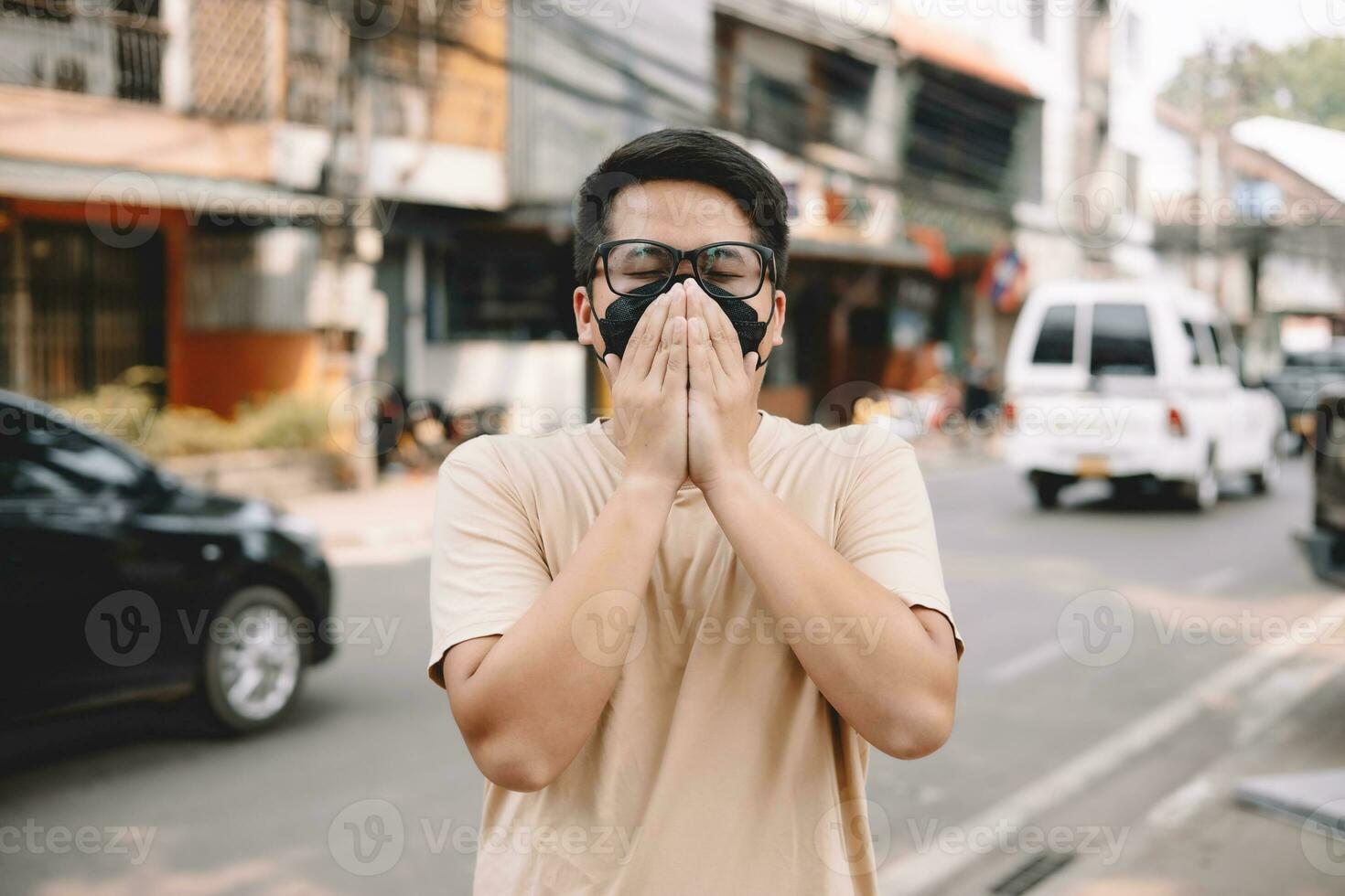 Asian young man wearing face mask to protect PM 2.5, protect pollution, anti smog and viruses on road in the city. Global warming concept. Healthcare concept. Environmental pollution concept. photo