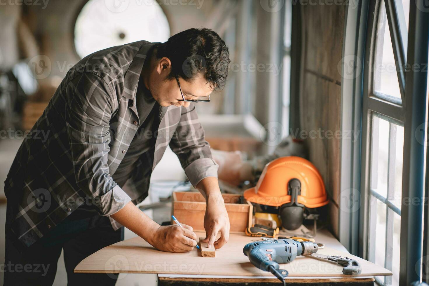 Asian carpenter working with equipment tools on wooden table in carpentry shop. Concept working of carpenter. Professional working wooden man. photo