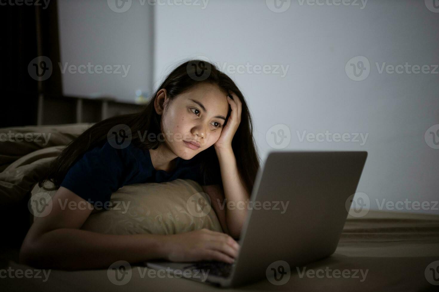Young asian women work late at night stressed out. Tired and exhausted from working on computer laptop in the bedroom. photo