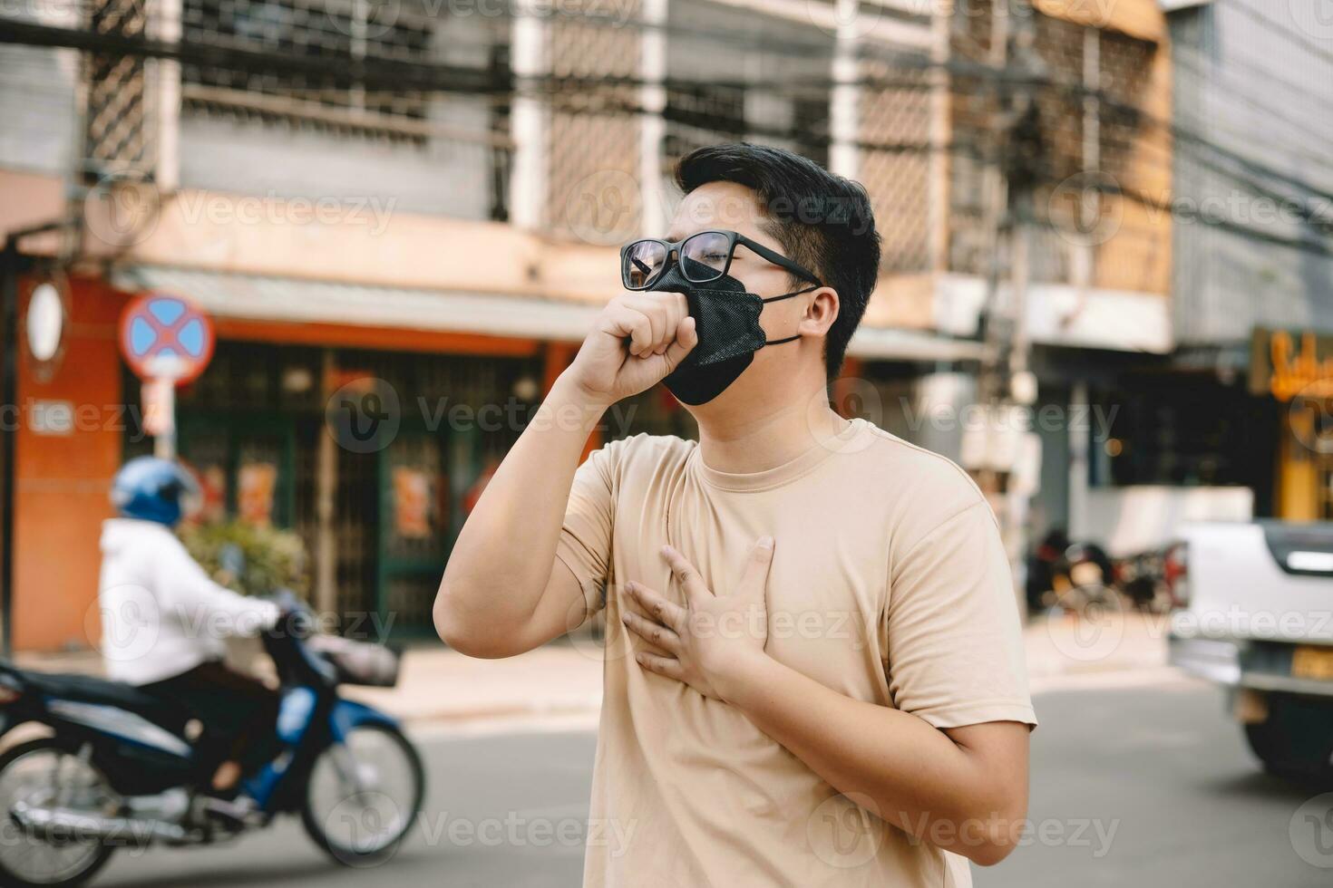 Asian young man wearing face mask to protect PM 2.5, protect pollution, anti smog and viruses on road in the city. Global warming concept. Healthcare concept. Environmental pollution concept. photo