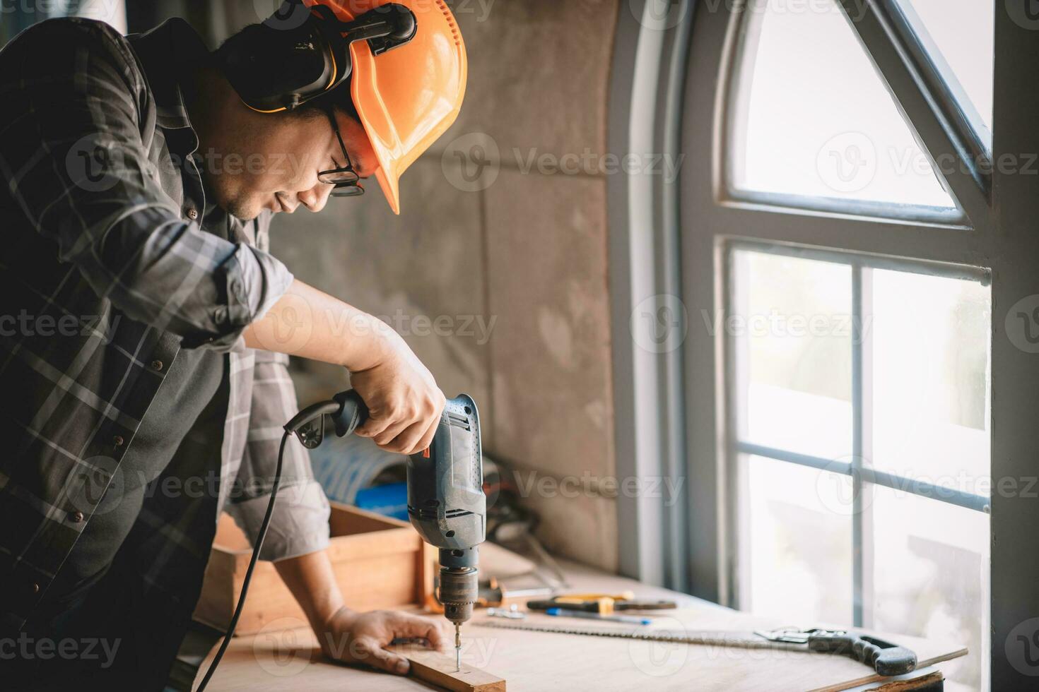 Close up of male mechanic holding electric cordless screwdriver drill with wood screw in the factory. Working with the screw. Professional carpenter. photo