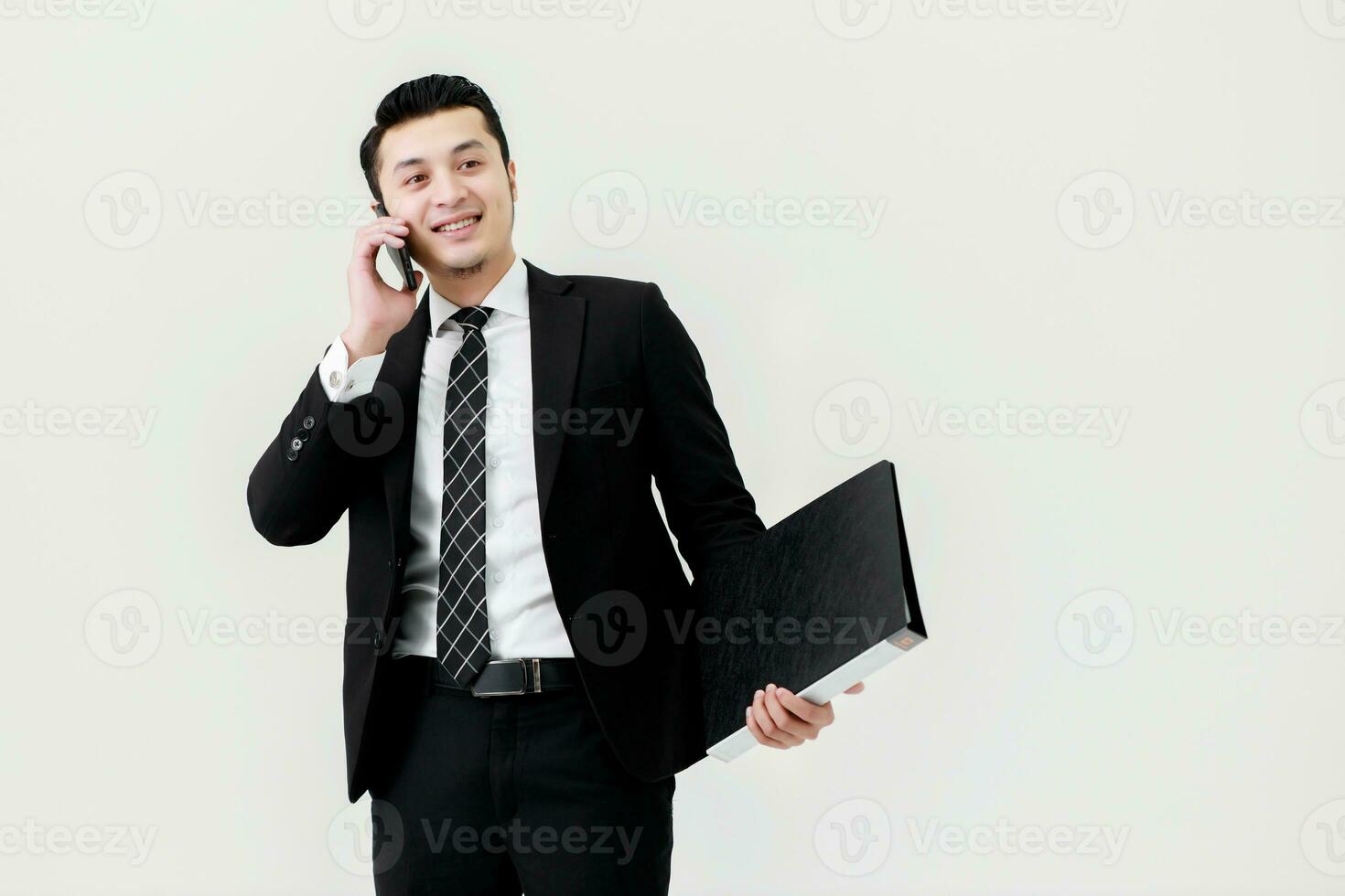 Business Asian man holding a fascicule with documents and using a smartphone for contact work in office on white background. photo