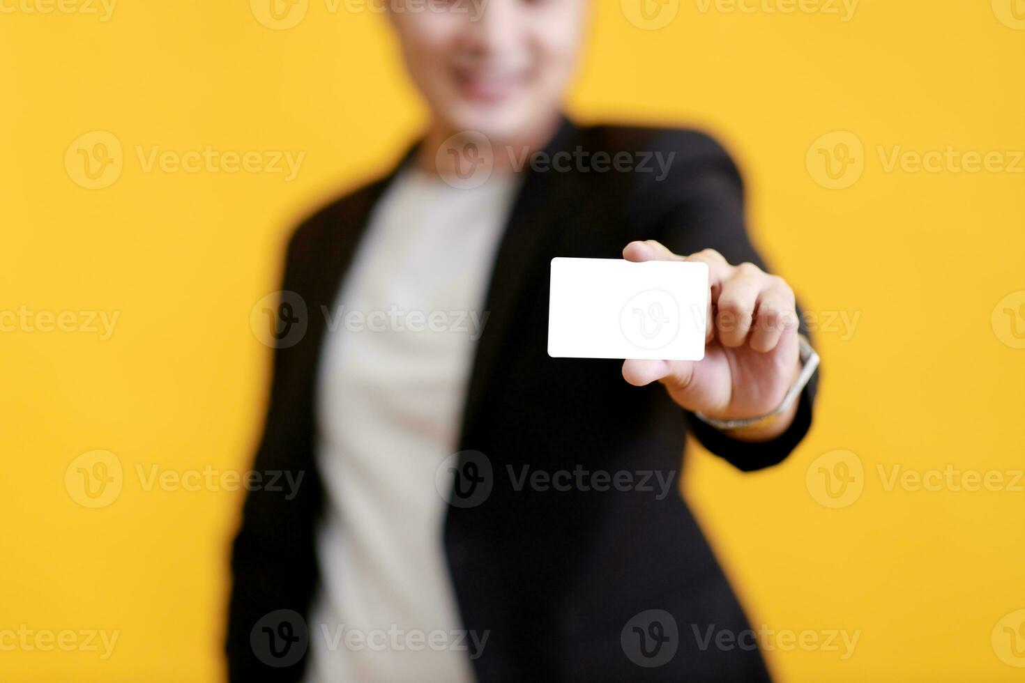 Young Asian man shows his credit card on a yellow background. photo