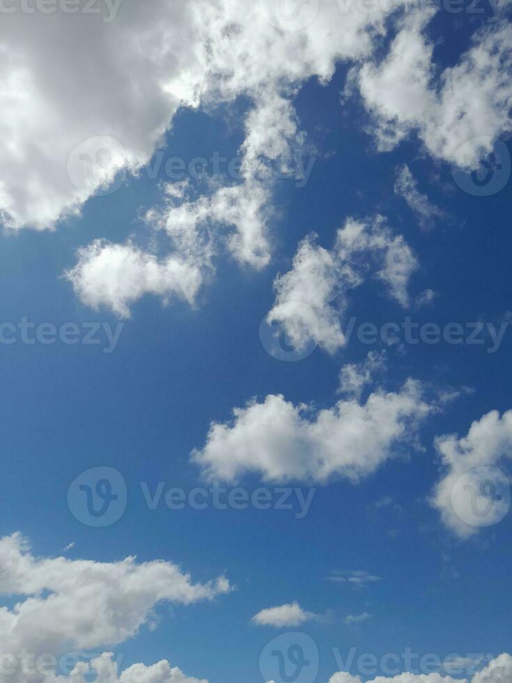 White clouds in the blue sky. Beautiful bright blue background. Light cloudy, good weather. Curly clouds on a sunny day. photo