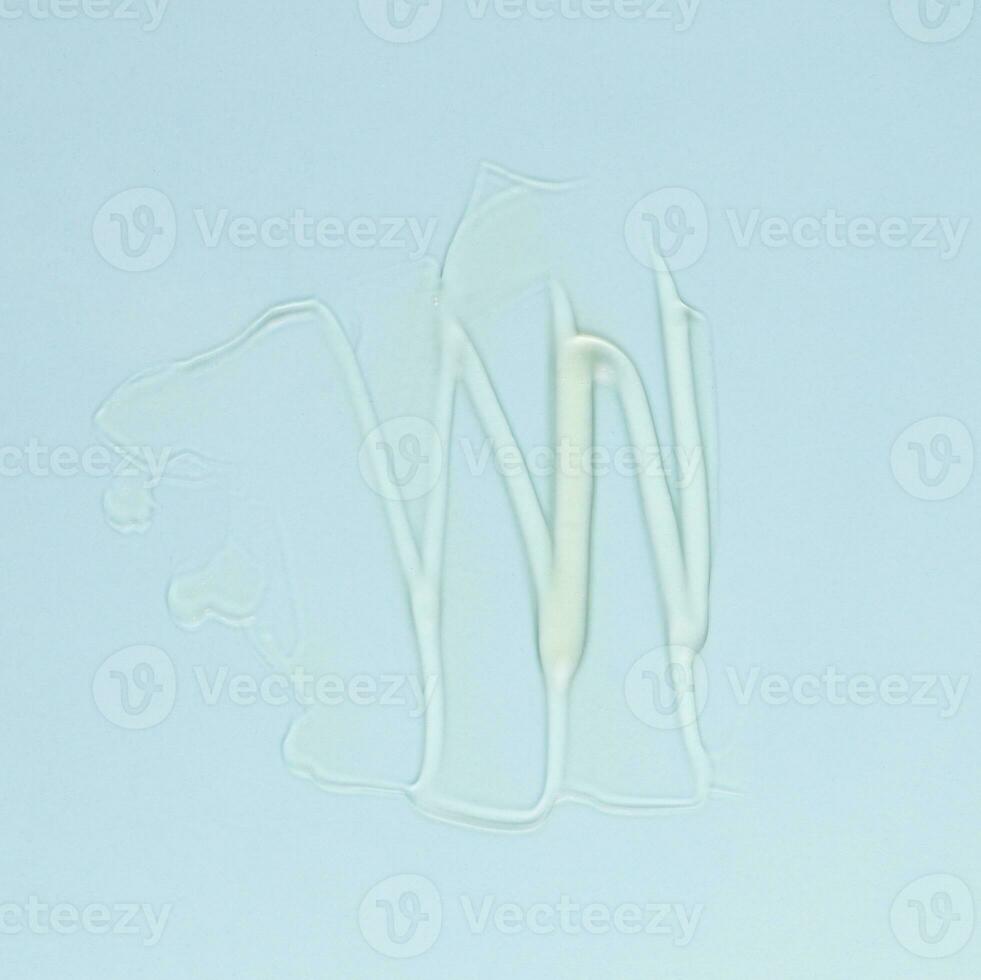 Smear of transparent cream for face and body on a blue background photo