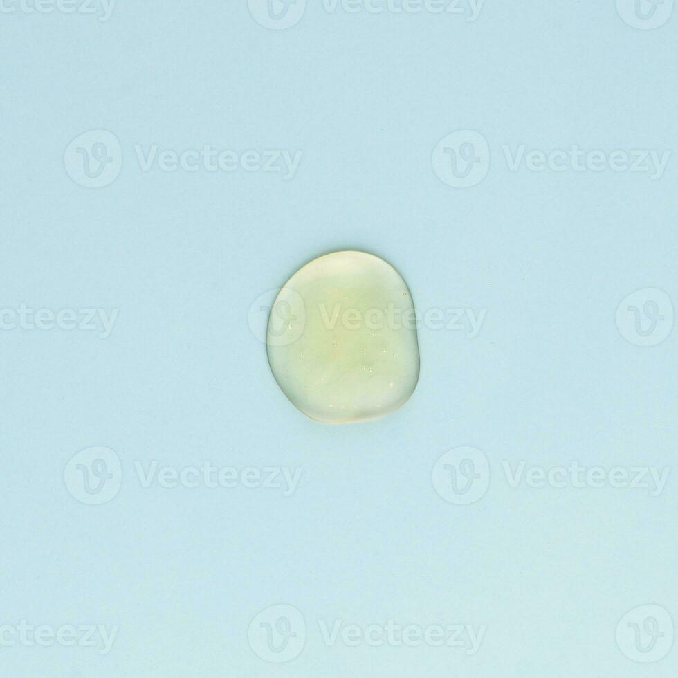 Drop of transparent face and body cream on a blue background photo