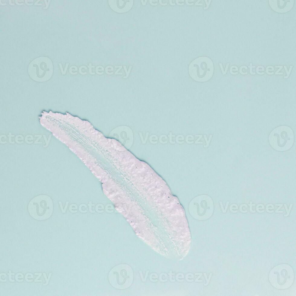 Smear of white cream for face and body on a blue background photo