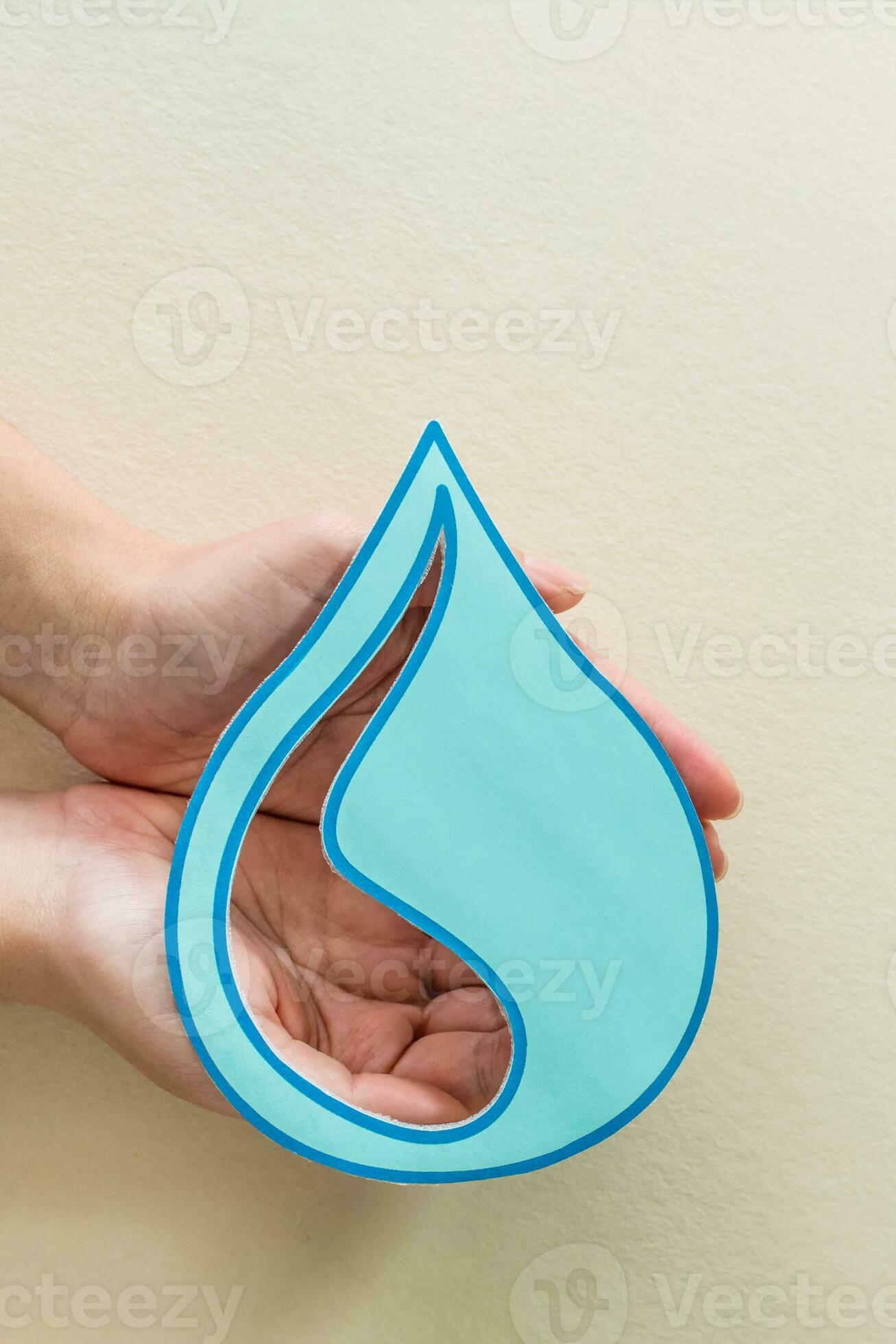 Woman hands holding paper cut water drop on beige background. Clean