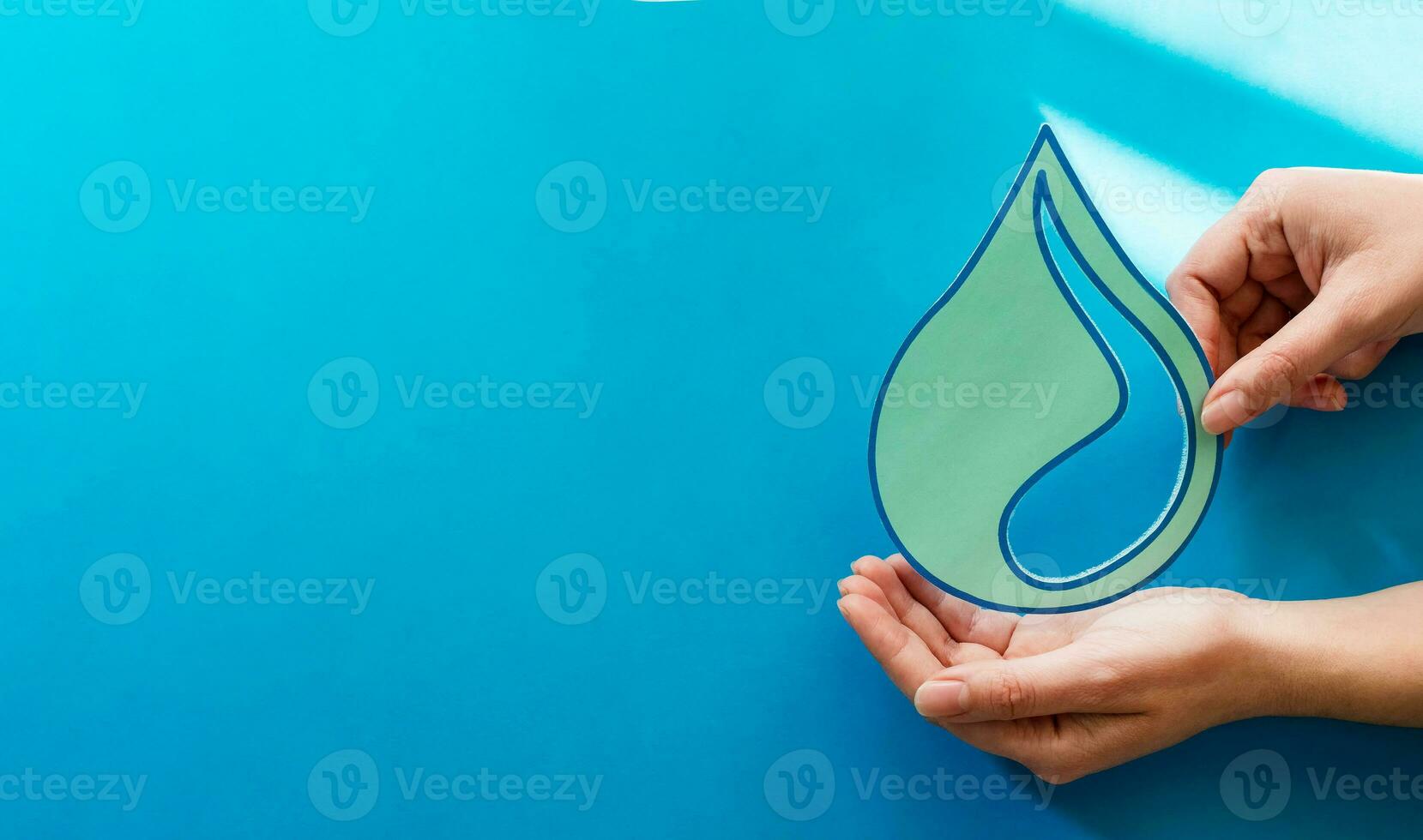 Woman hands holding paper cut water drop on blue background. Clean water and sanitation, saving water. World Water Day. Ecology concept. photo
