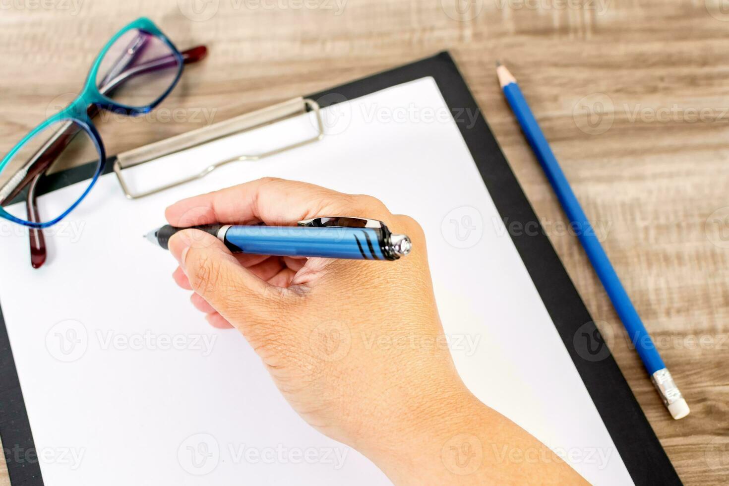 Close up of female hands writing on notebook, pencil on wooden table. Education concept. photo