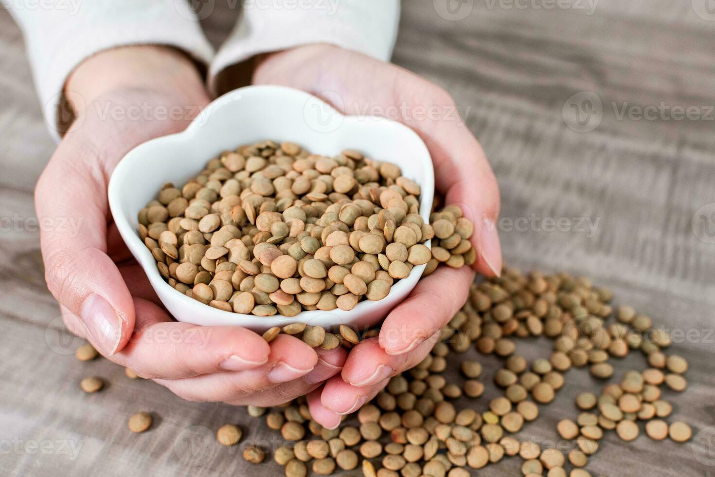 Close-up Of Hands holding bowl with raw lentils. photo