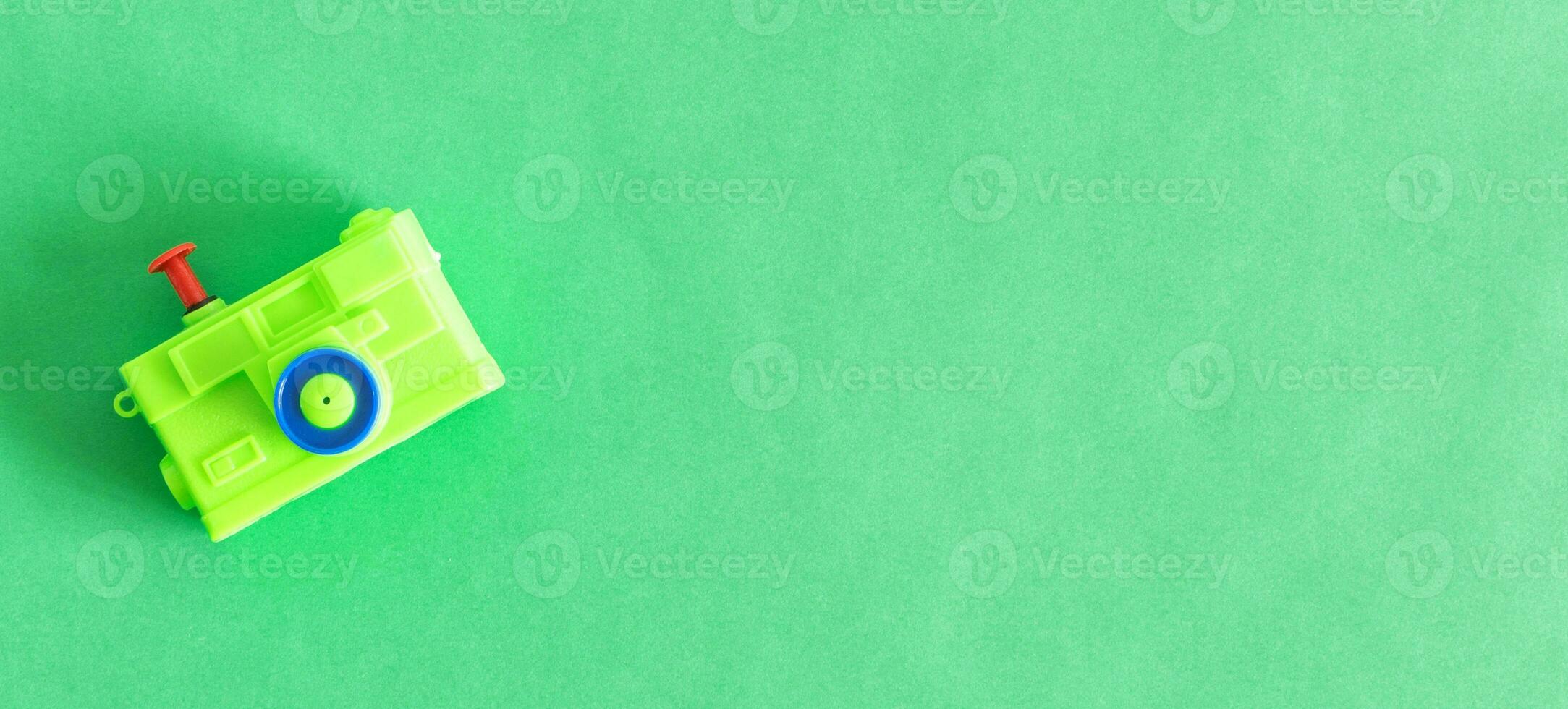 Isolated toy camera, green color, on green background. Top view. photo