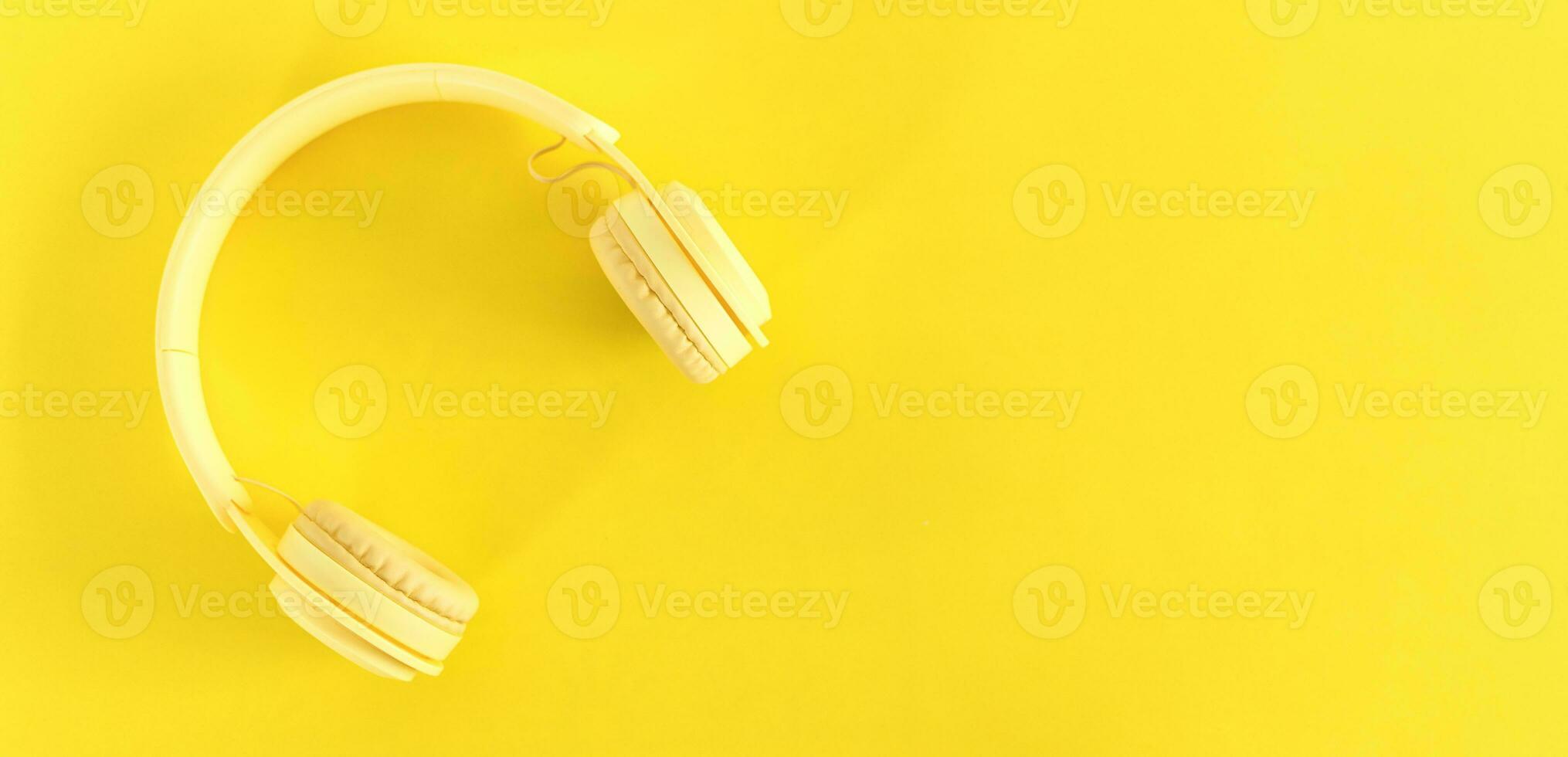 Top view of headphones on yellow background. Minimalist photo of earphones with copy space. Yellow DJ headphones.