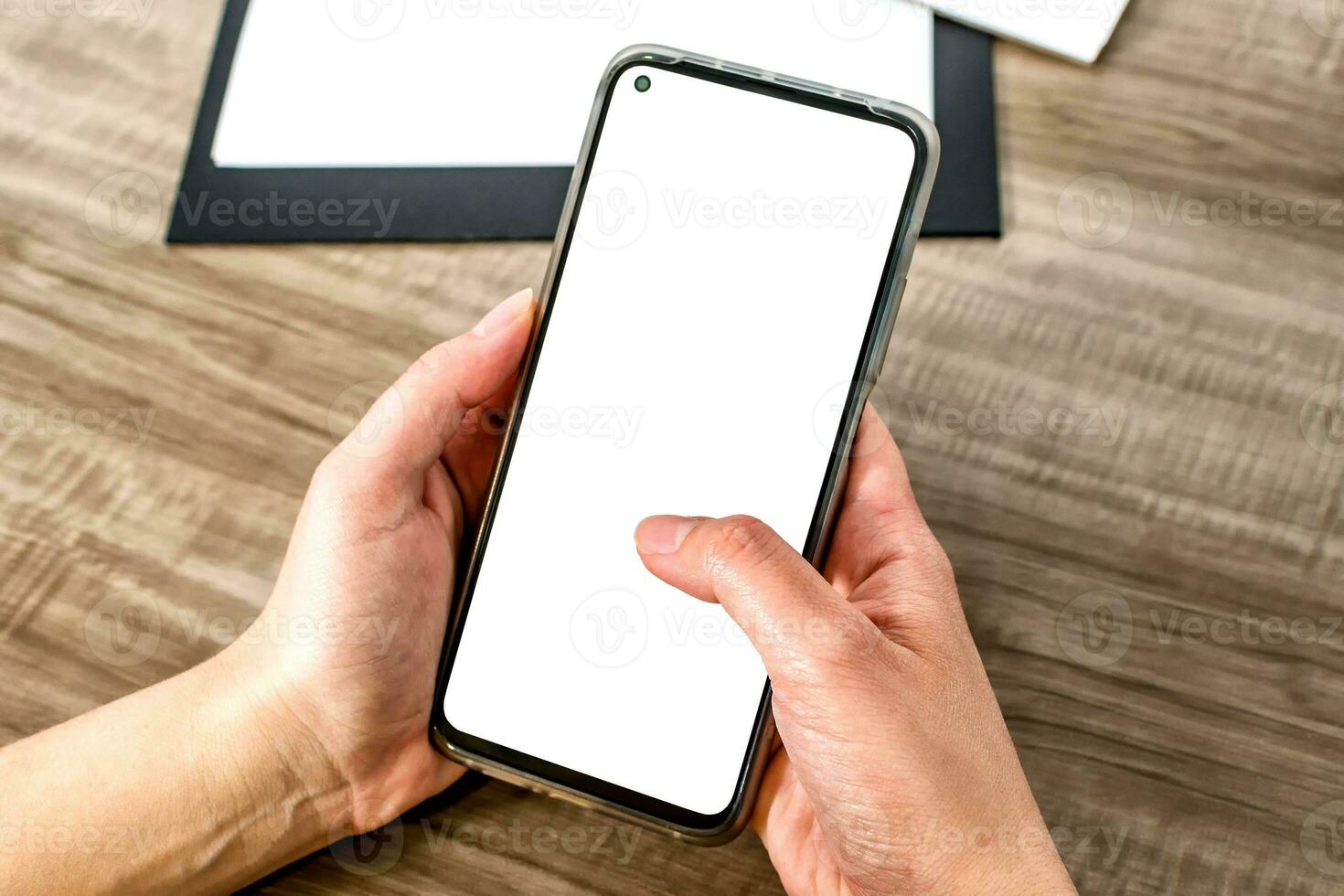 Top view mockup image of a hands holding mobile phone with blank white screen. photo