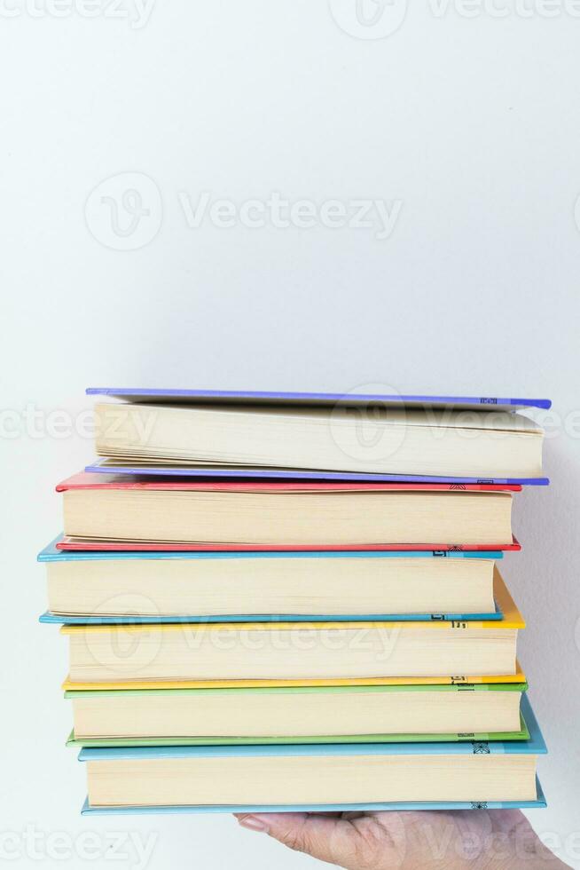 Female hand holding stacked books on white background. Study. Textbooks. photo