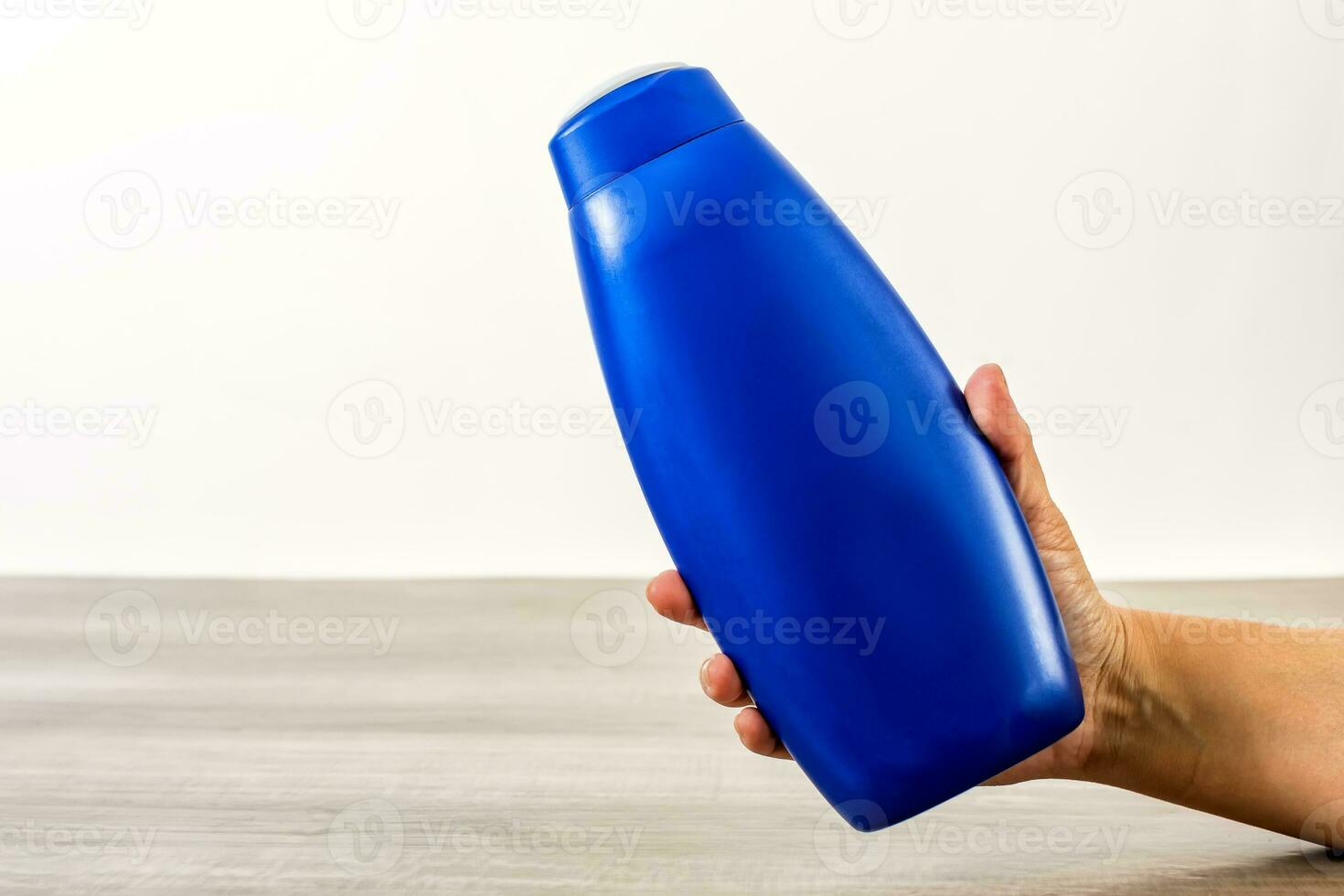 Female hand holding empty shampoo bottle. photo