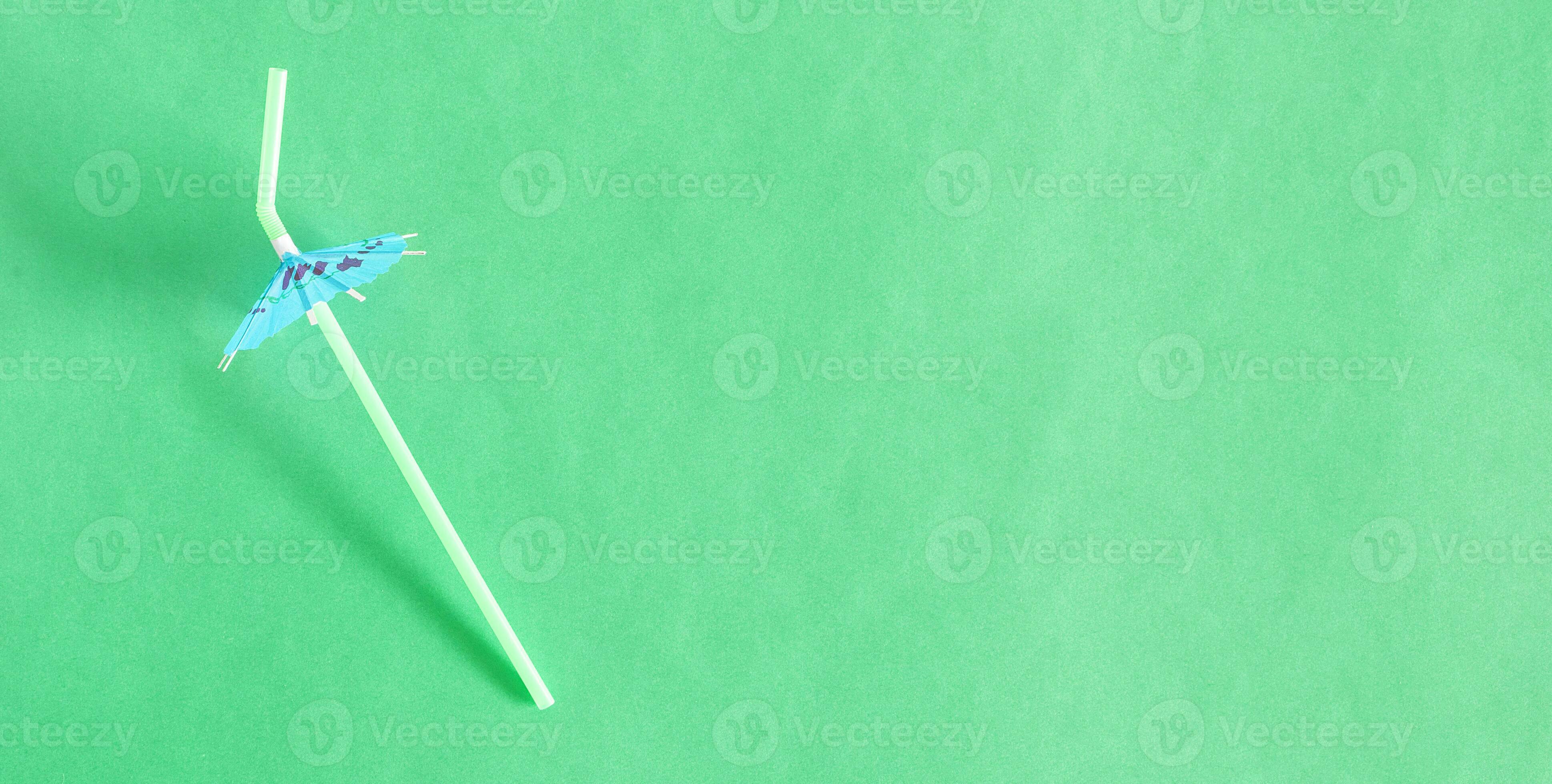 Top view of cocktail flexible straw with umbrella, on green background