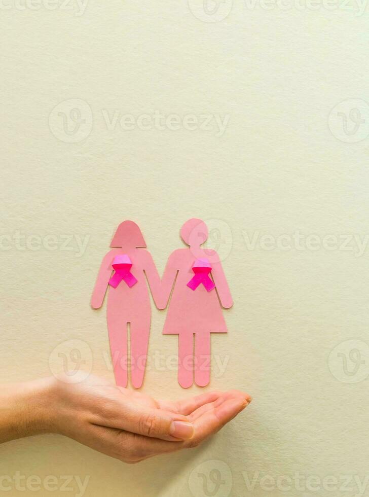 Woman hand holding girl silhouette with pink ribbon, breast cancer awareness. World cancer day concept. photo