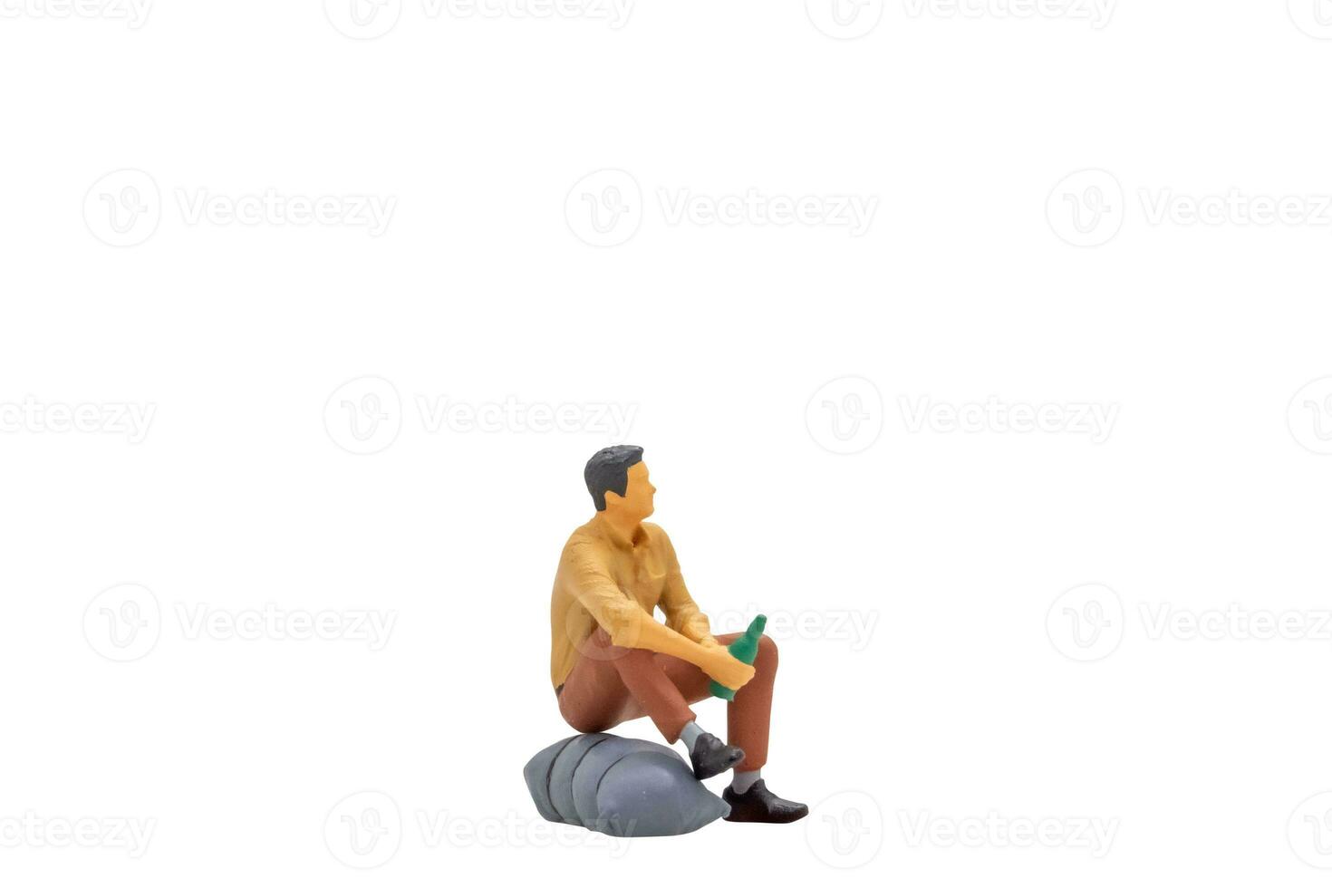 Miniature people Young man sitting on a rock isolated on white background photo