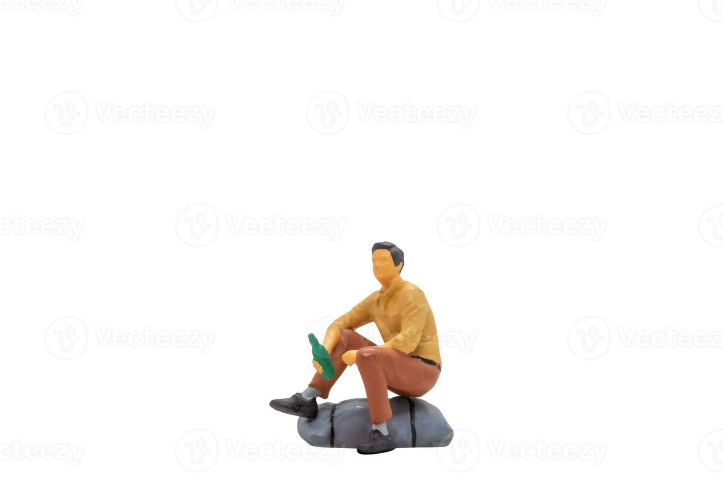 Miniature people Young man sitting on a rock isolated on white background photo
