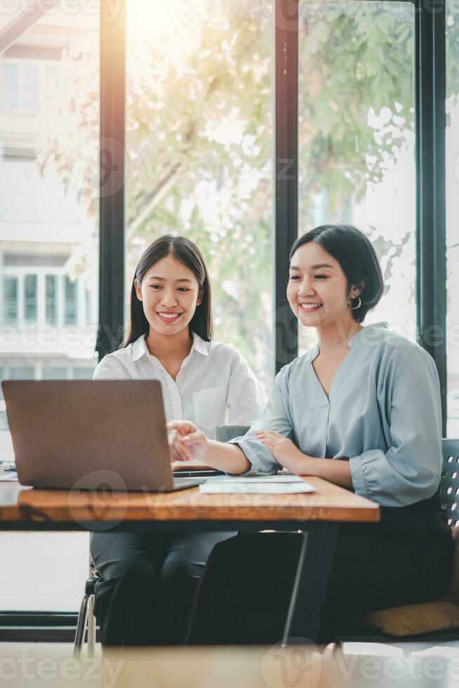 Two businesswoman working together on laptop computer. Creative female executives meeting in an office using laptop pc and smiling. photo