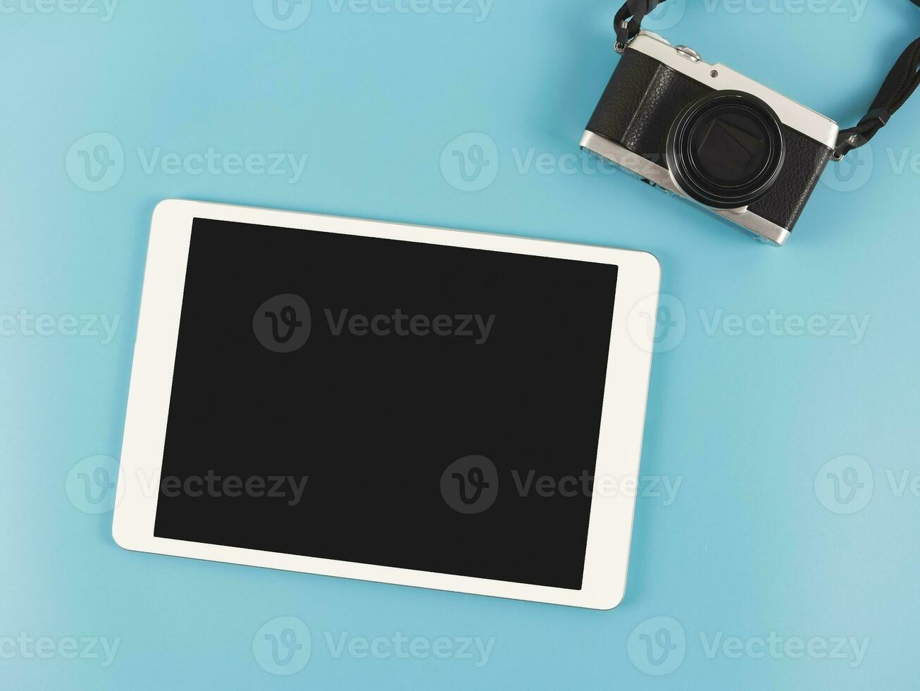 flat lay of digital tablet with blank black screen and digital camera isolated on blue background. photo