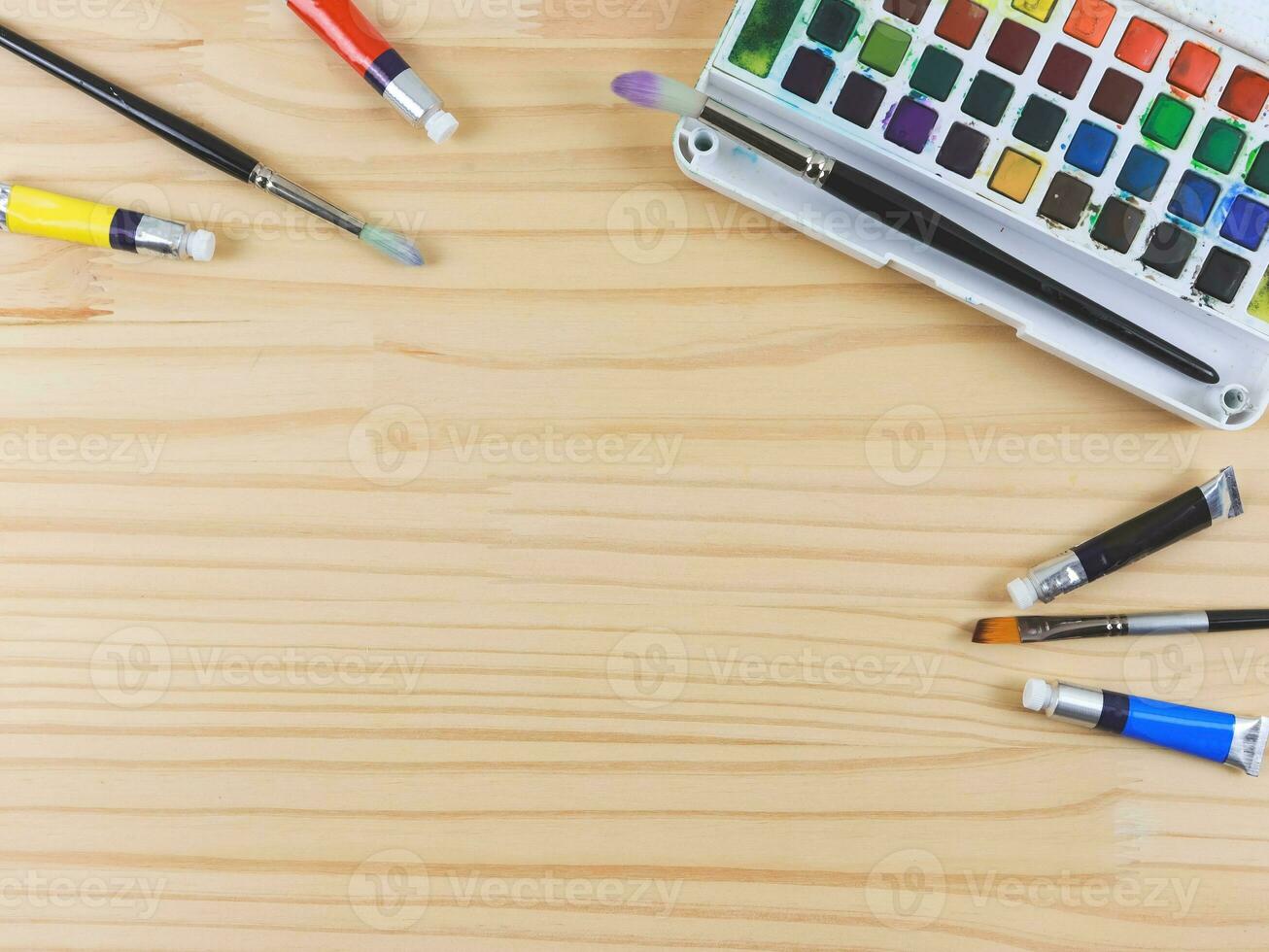 flat lay of artist workspace. Drawing tools, stationary supplies, Watercolor paints and brushes on wooden table, copy space. photo