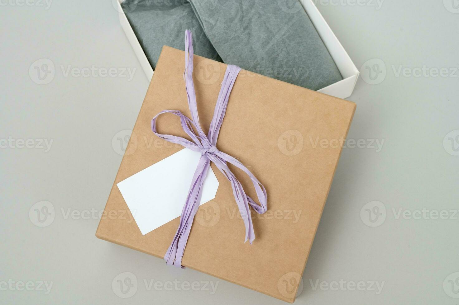 cajas para parcelas hecho de Kraft papel en un gris antecedentes. regalo caja con un etiqueta para texto, logo. foto
