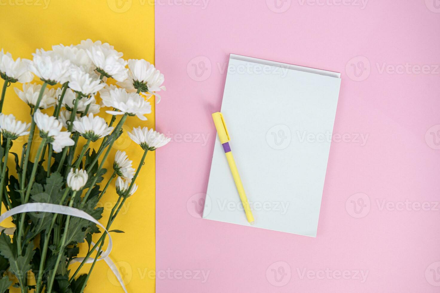 A clean notebook and pen on a light pink table. Mockup with a bouquet of flowers on a yellow table photo