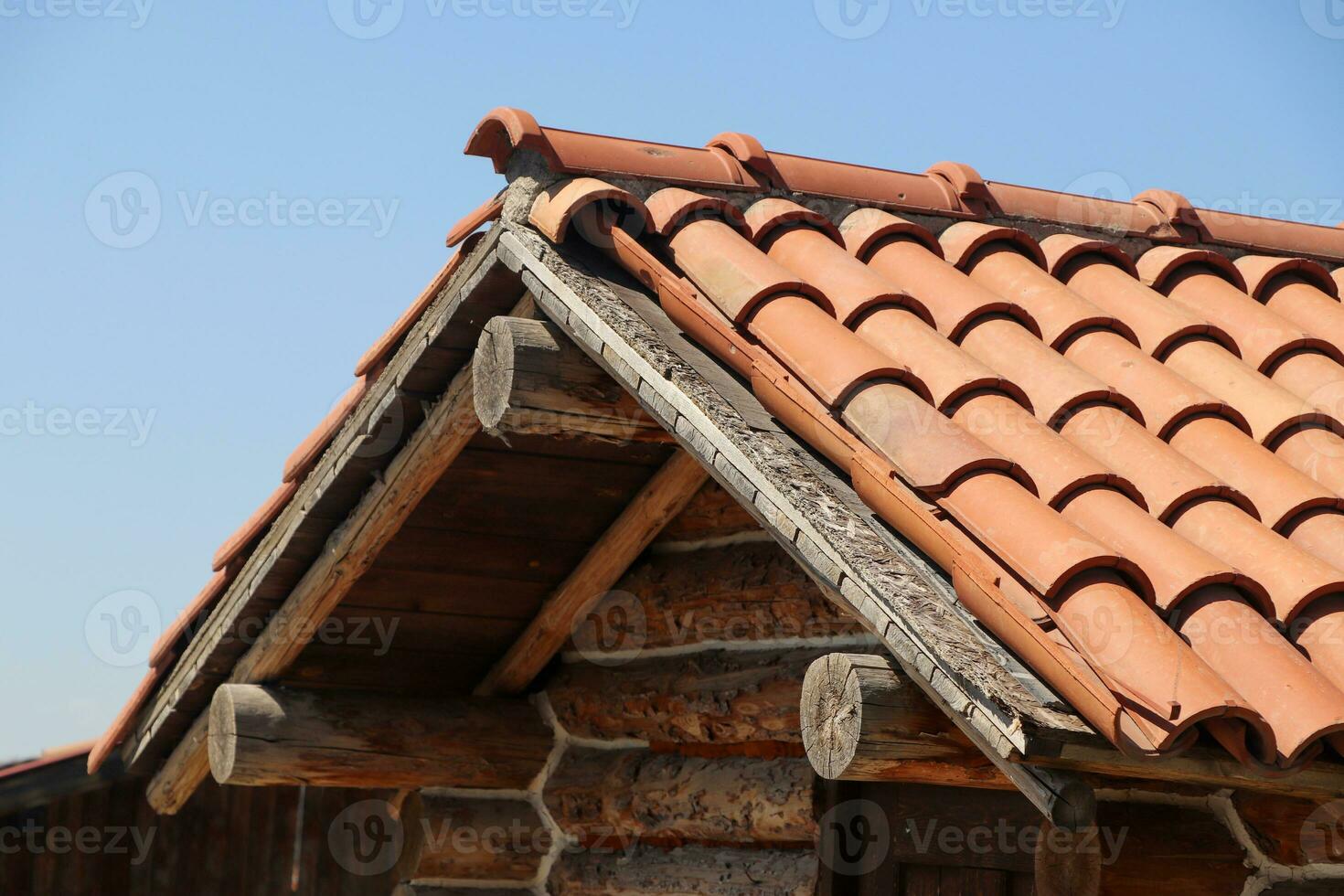 Fragment of old, worn brown tile roof on the right of house photo