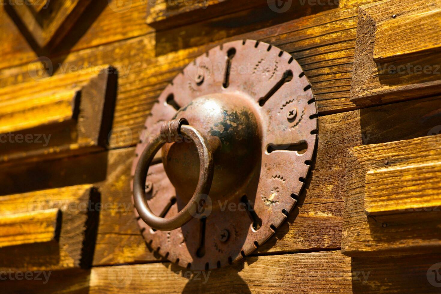 Close up shot of an old wrought iron knocker on a rustic wooden door photo