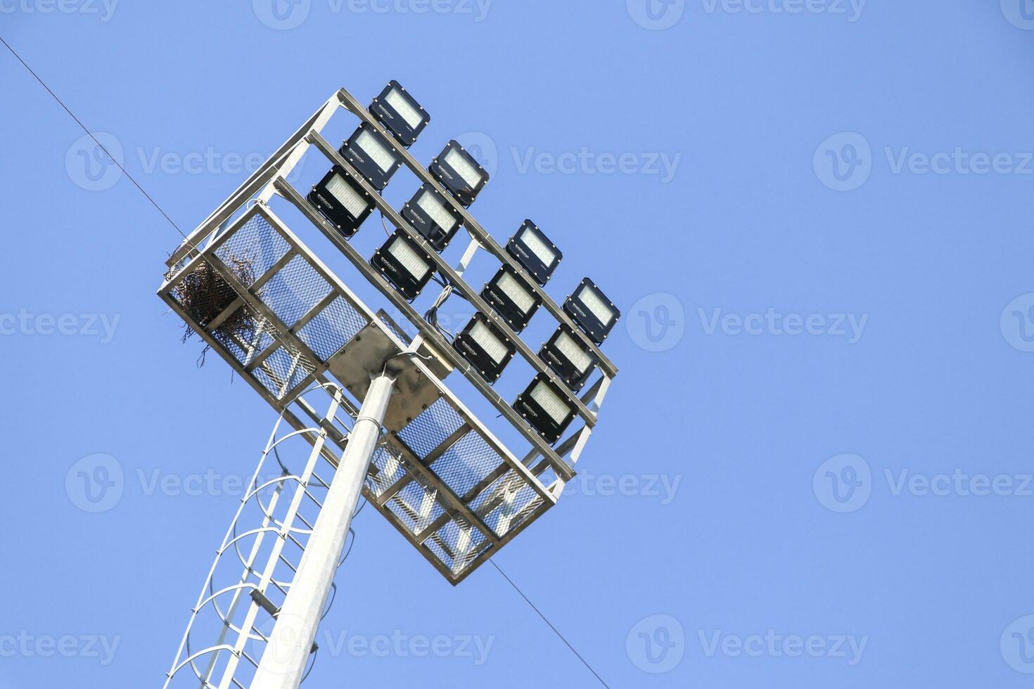 Silhouette of a spotlight on a blue sky background. Lamps for stadium lighting. photo